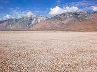 some mountains with rocks and gravel in between them as well as a large lake surrounded by grass and sand