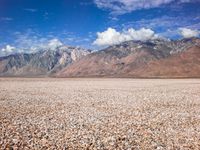 some mountains with rocks and gravel in between them as well as a large lake surrounded by grass and sand