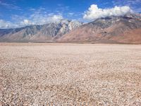 some mountains with rocks and gravel in between them as well as a large lake surrounded by grass and sand