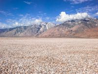 some mountains with rocks and gravel in between them as well as a large lake surrounded by grass and sand