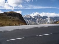 a large mountain with some snow on the top of it and an empty road with a few white lines on it