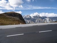 a large mountain with some snow on the top of it and an empty road with a few white lines on it