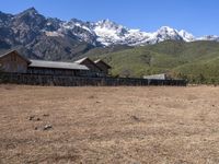 large mountain with snow covered peaks in the background and building near by field of dried grass