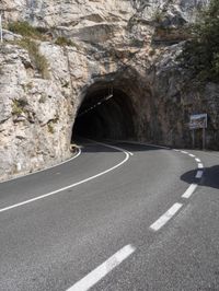 a motorcycle is going through the tunnel in the mountains area of italy as a stop sign shows