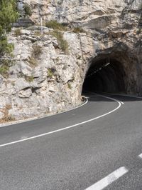 a motorcycle is going through the tunnel in the mountains area of italy as a stop sign shows