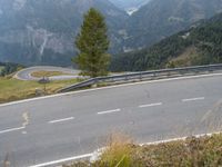 an asphalt road with white lines in it, leading through mountains to a winding mountain pass