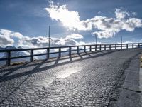 a paved road with large fence near the top of it and snow on the ground