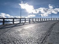 a paved road with large fence near the top of it and snow on the ground