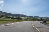 an empty road near mountains with hills in the background on a clear, sunny day