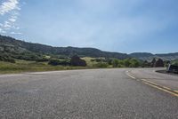 an empty road near mountains with hills in the background on a clear, sunny day