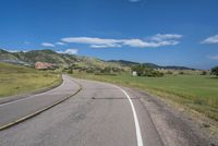 an empty road near mountains with hills in the background on a clear, sunny day