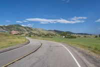 an empty road near mountains with hills in the background on a clear, sunny day