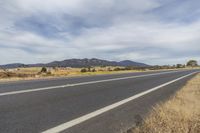 a highway with no cars or vehicles in the area on one side, with mountains in the background