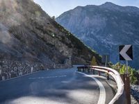 a car drives along an empty mountain side road in the daytime sunshine and lens flares out
