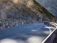 a car drives along an empty mountain side road in the daytime sunshine and lens flares out