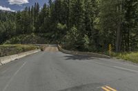 a mountain side road with two lanes, and a road sign that says to keep drivers safe