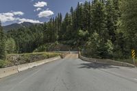 a mountain side road with two lanes, and a road sign that says to keep drivers safe