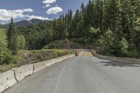 a mountain side road with two lanes, and a road sign that says to keep drivers safe