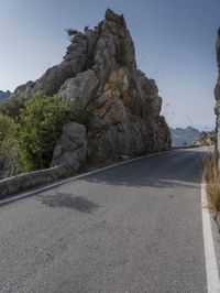 the road in the mountains is lined by rocks and boulders with a sky background and birds flying overhead