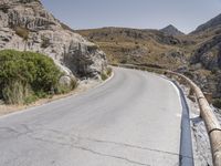 a paved mountain road winds its way through the mountainside at a scenic angle with steep cliffs in the background