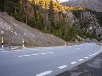 a curve road with a mountain in the distance and trees and mountain peaks in the background