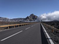 an empty roadway and clouds over mountains, during the day on a sunny day with clear skies