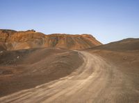 a dirt road and mountains that are almost barren with dirt on the ground in front