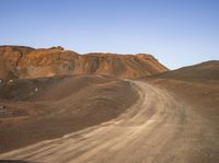 a dirt road and mountains that are almost barren with dirt on the ground in front