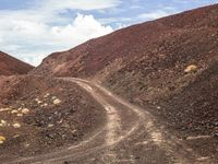 a dirt road with gravel and rocks running across it in the desert area of a mountain