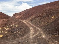 a dirt road with gravel and rocks running across it in the desert area of a mountain