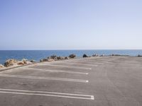 a deserted parking lot on the edge of a beach next to a sea in a clear day