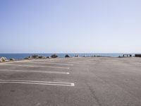 a deserted parking lot on the edge of a beach next to a sea in a clear day