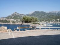 a bench in the middle of a parking lot next to some mountains and water near rocks and grass