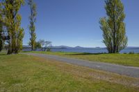 park path with scenic views over water, and green grass on both sides of the road