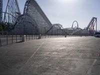 some parking lot with various roller coasters in background and two cars parked near them