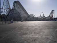 some parking lot with various roller coasters in background and two cars parked near them