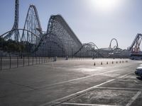 some parking lot with various roller coasters in background and two cars parked near them