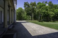 a path that is made out of a building and grassy area in front of trees