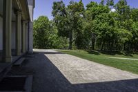 a path that is made out of a building and grassy area in front of trees