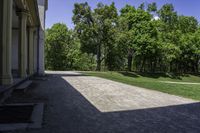 a path that is made out of a building and grassy area in front of trees