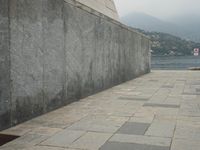 a long pathway in front of a concrete building with mountain views behind it in a city area