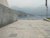 a long pathway in front of a concrete building with mountain views behind it in a city area