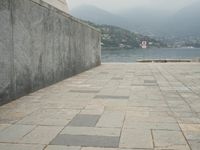 a long pathway in front of a concrete building with mountain views behind it in a city area