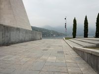 a long pathway in front of a concrete building with mountain views behind it in a city area