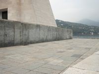 a long pathway in front of a concrete building with mountain views behind it in a city area