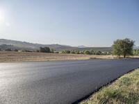 a paved country road next to some mountains and a grassy plain area on one side