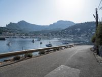 paved road in front of water with mountains in background and boat launch at right corner