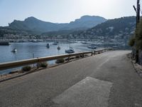 paved road in front of water with mountains in background and boat launch at right corner