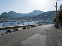 paved road in front of water with mountains in background and boat launch at right corner