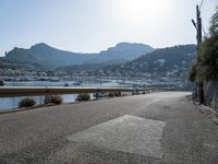 paved road in front of water with mountains in background and boat launch at right corner